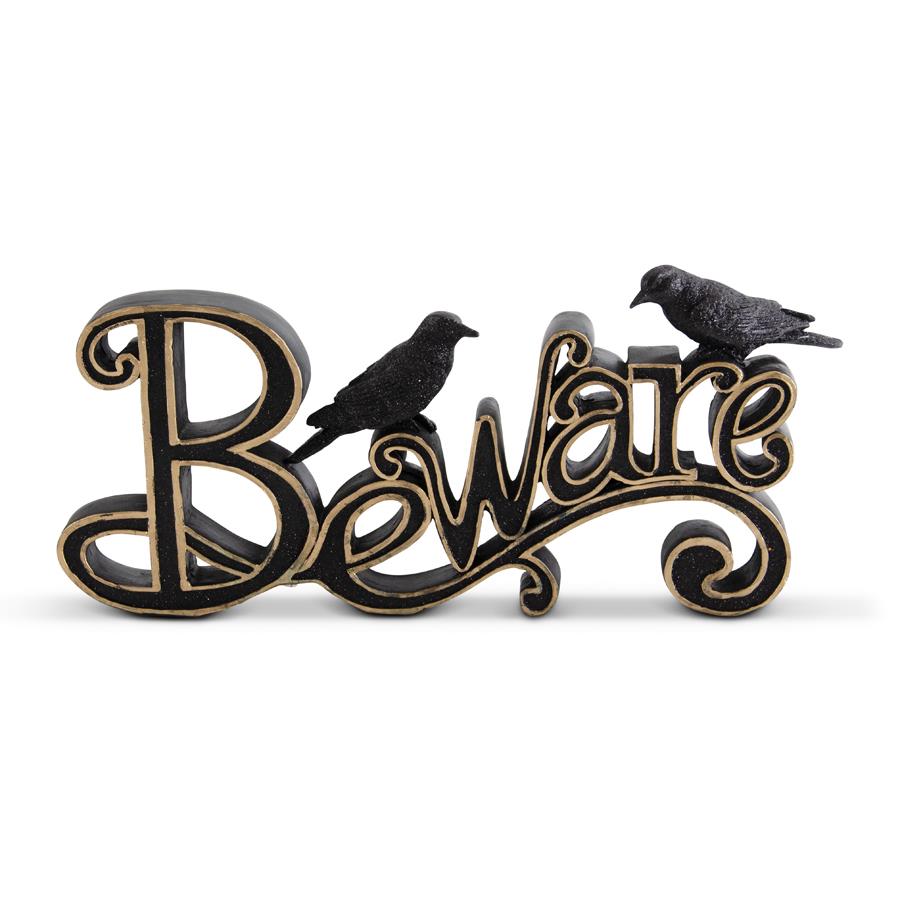 A black and gold 'Beware' tabletop sign with a resin cutout of the word 'Beware' and two crows perched on it
